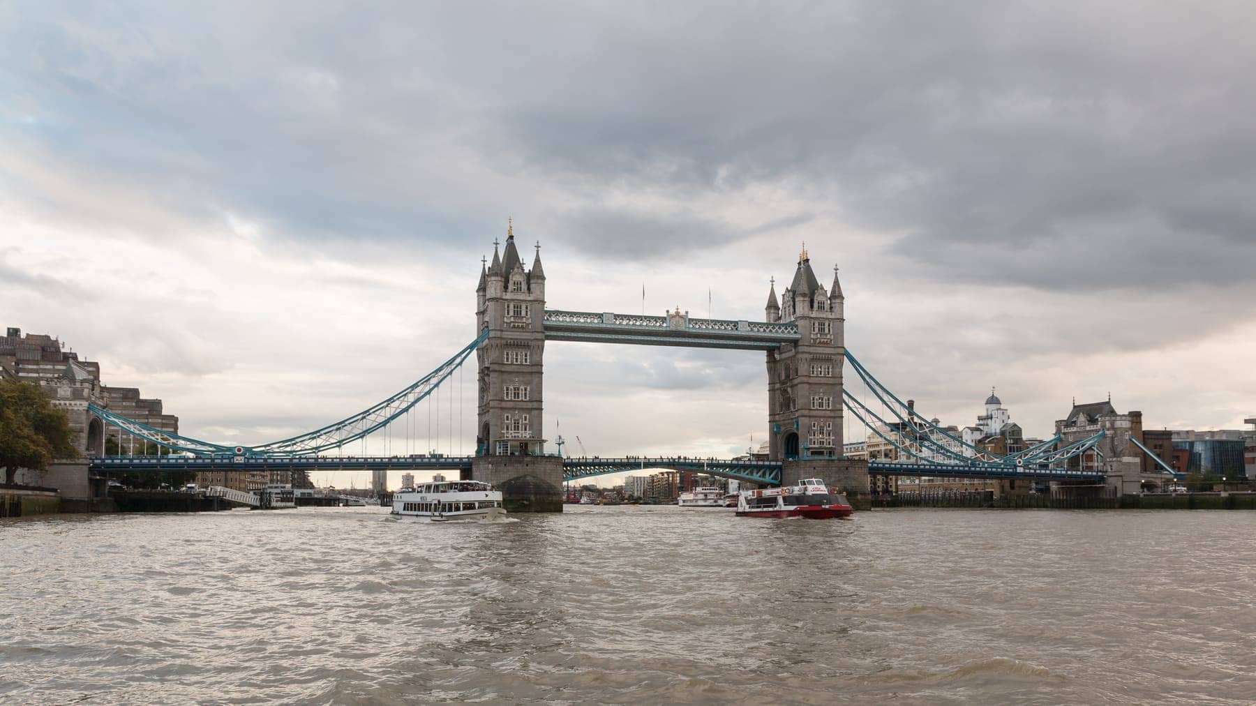 Tower Bridge crossing the River Thames in London, photographed from the river under a cloudy sky